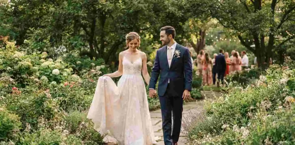 Bride and groom walking through a garden together
